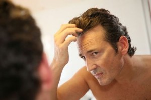 Man looking at his receding hairline in the mirror