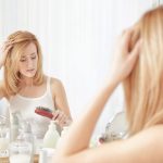 woman brushing her hair struggling with hair loss