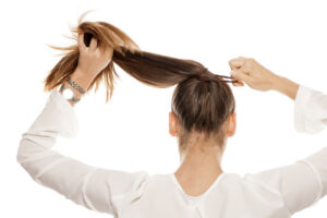 Woman putting her hair up in a tight ponytail