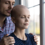 Young husband holding his wife who is struggling with hair loss from cancer