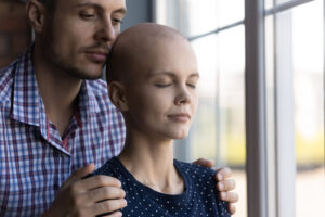 Young husband holding his wife who is struggling with hair loss from cancer