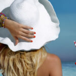 woman covering her hair with a beach hat protecting it from the sun