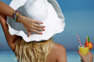 woman covering her hair with a beach hat protecting it from the sun