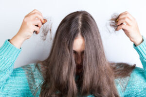 Girl holding her lost hair in hands, on a white background