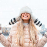 Girl outside in the snow protecting her hair with a hat from the harsh winter conditions