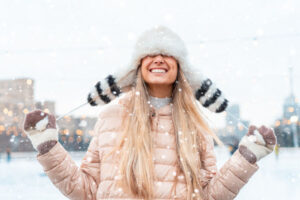 Girl outside in the snow protecting her hair with a hat from the harsh winter conditions